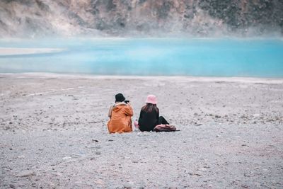 Rear view of couple sitting on beach