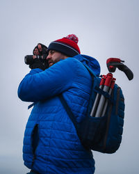 Rear view of man photographing against sky