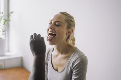 Doctor examining female patient with mouth open in clinic