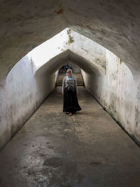 Rear view of woman walking in tunnel