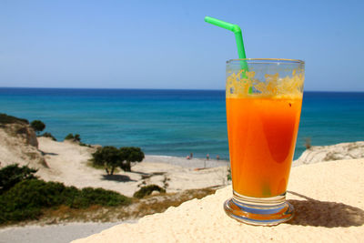 Drink on table at beach against blue sky