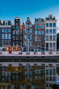 Reflection of buildings in canal against blue sky