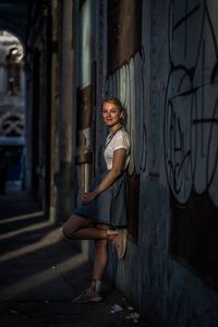 Full length portrait of woman standing by wall