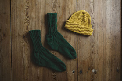 Knitted hat and socks on wooden background