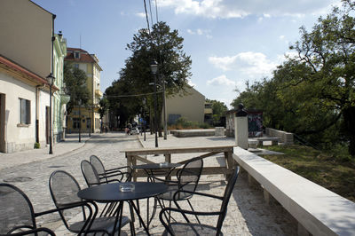 Empty chairs and tables against buildings in city