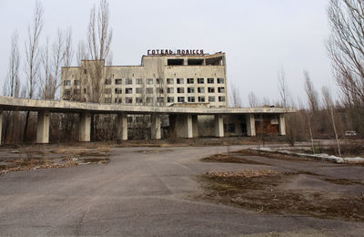 Abandoned building by road against sky in city