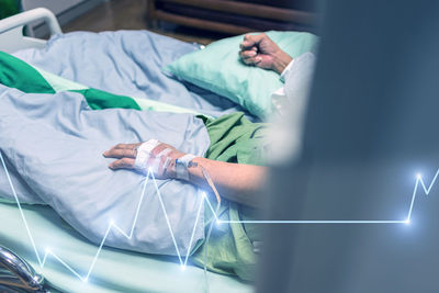 Digital composite image of person with iv drop and pulse trace on bed at hospital 