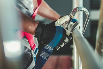 Midsection of worker attaching hook on railing