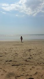 Woman walking at beach against sky