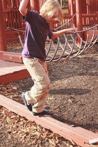 Portrait of boy walking across playground equipment 