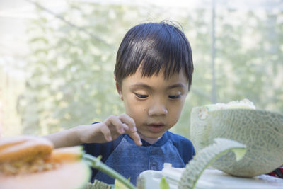 Close-up of boy standing by muskmelons