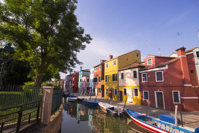 Boats moored in canal amidst buildings against sky