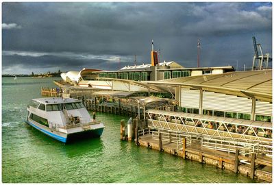 Buildings by river against cloudy sky