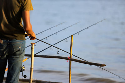 A man stands at the fishing rod waiting for the fish to eat the bait.