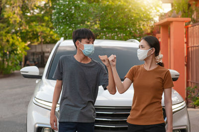 Young woman with boy standing by car outdoors