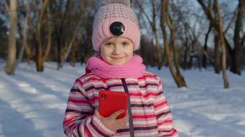 Portrait of girl holding mobile phone during winter