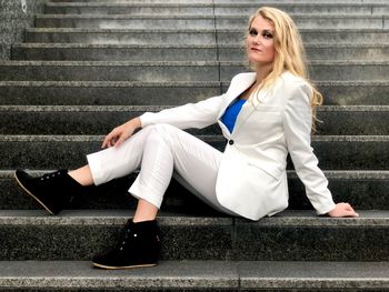 Full length portrait of young woman sitting on steps