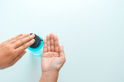 Close-up of woman hand holding bottle against white background