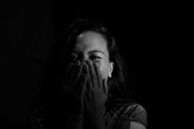 Close-up portrait of young woman against black background