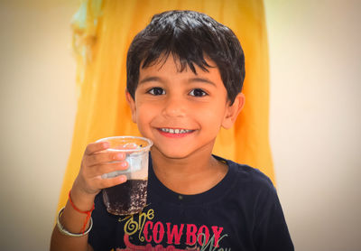 Portrait of smiling boy holding cold drink at home