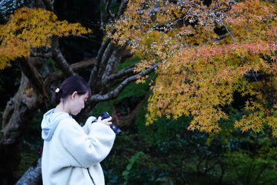 Side view of young woman holding autumn leaves