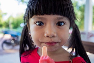 Close-up portrait of cute girl eating popsicle