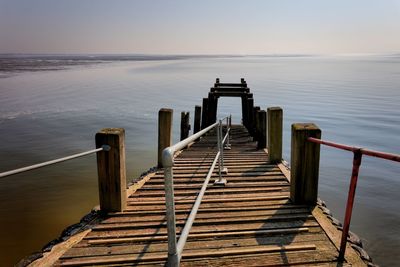 Wooden pier over sea against sky