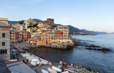 Italy, august 2020 people enjoying late afternoon at boccadasse little bay with setting sun.