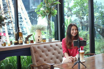 Portrait of young woman using phone while sitting on table