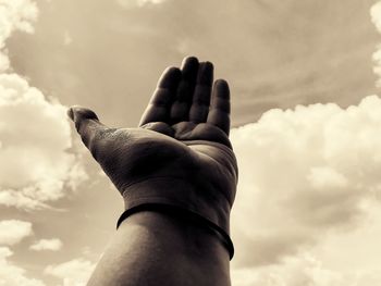 Low angle view of hand gesturing against sky