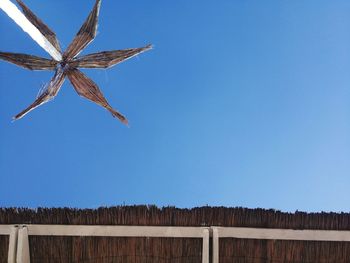 Low angle view of thatched roof against clear blue sky