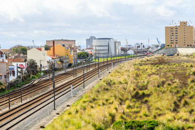 Train on railroad tracks by buildings in city against sky