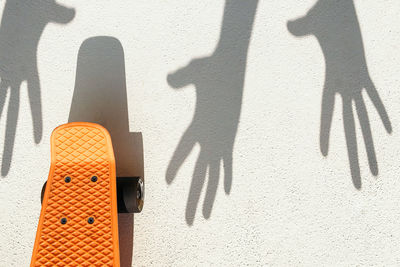 Close-up of skateboard with hand shadow on road