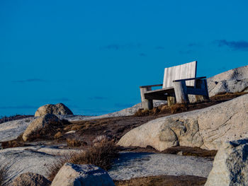 Built structure on rocks by sea against blue sky