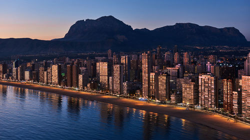 Panoramic view of illuminated cityscape against sky at sunset