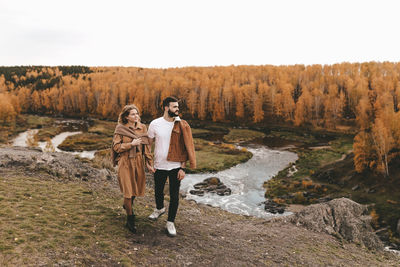 Full length of friends standing on land against sky