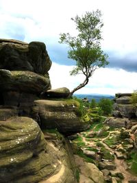 Stack of rocks on landscape against cloudy sky