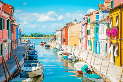 Boats moored on canal amidst buildings