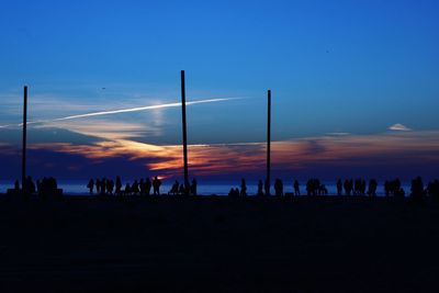 Silhouette people at beach against sky during sunset