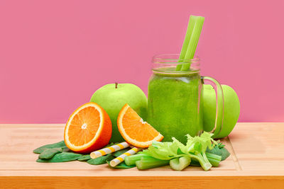 Green fruits on table against orange background