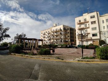 Road by buildings against sky in city