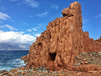 Rock formation at sea shore against sky