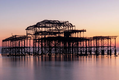 Silhouette pier over sea against clear sky during sunset