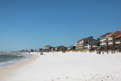 Panoramic view of beach and buildings against clear blue sky