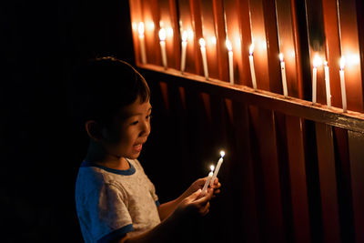 Rear view of boy holding illuminated candles