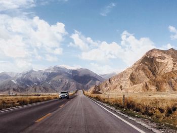 Road leading towards mountains against sky