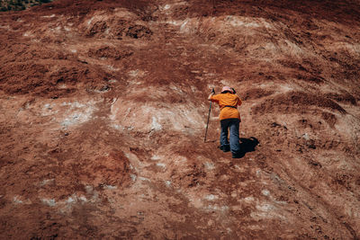 Rear view of a man walking uphill with nordic walking sticks