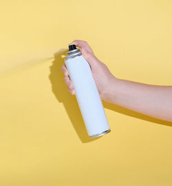 Hand holding can and spraying a product over a yellow background. mock up for  design. cleaning conc