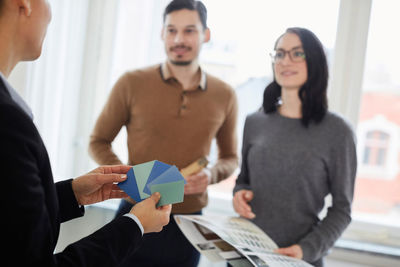 Cropped image of realtor showing color samples to couple in new home