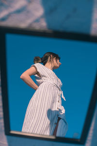 Side view of woman standing against blue wall